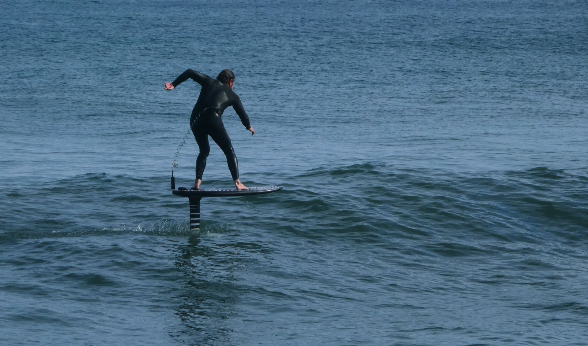 Person surft mit Efoil auf den Wellen im Meer