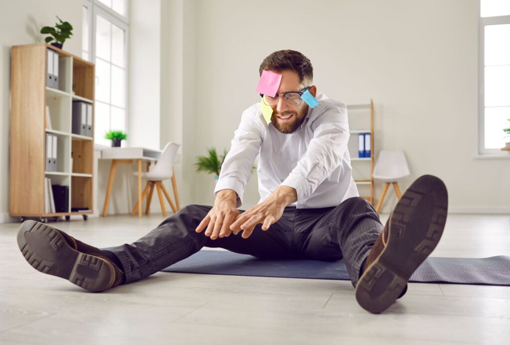 Mann macht Stretching mit Post-its im Büro.