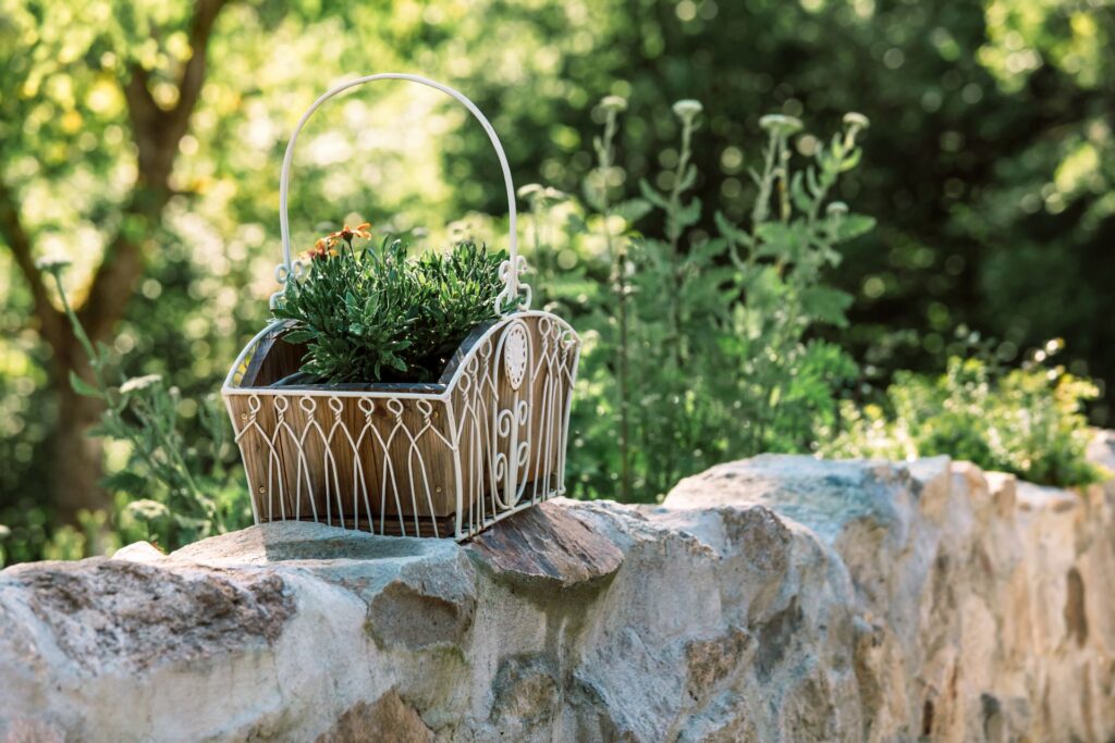 Pflanzkorb aus Metall als Gartendeko auf Steinmauer